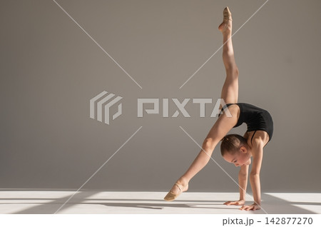 A little girl gymnast does a handstand. Copy space. A little girl gymnast does a handstand. Copy space. 142877270