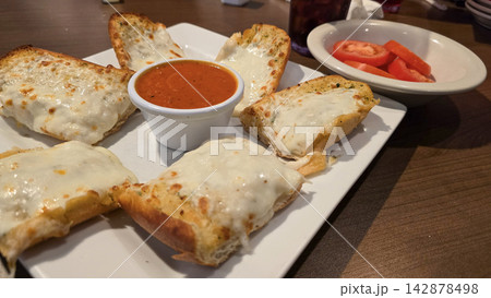 Cheesy Garlic Bread With Marinara Sauce and Sliced Tomatoes on a White Plate 142878498