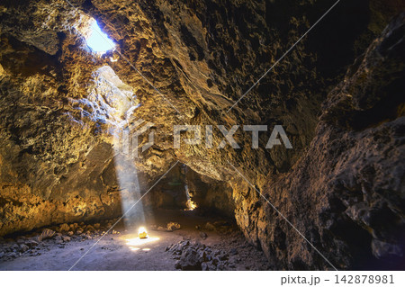 Lava Tube Sunbeam Illuminating Volcanic Cave Interior with Dramatic Rock Formations Lava Tube Sunbeam Illuminating Volcanic Cave Interior with Dramatic Rock Formations 142878981