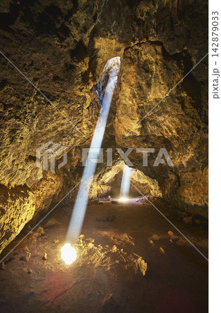 Sunbeams Illuminate Mojave Lava Tube Cave Interior with Dramatic Volcanic Rock Texture Sunbeams Illuminate Mojave Lava Tube Cave Interior with Dramatic Volcanic Rock Texture 142879033