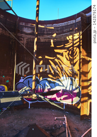Abandoned Industrial Tank Interior With Graffiti Art and Dramatic Shadow Play Abandoned Industrial Tank Interior With Graffiti Art and Dramatic Shadow Play 142879174