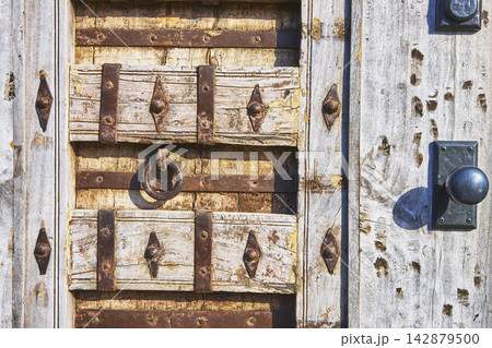Close Up Weathered Wooden Door With Iron Hardware And Rustic Ring Handle 142879500