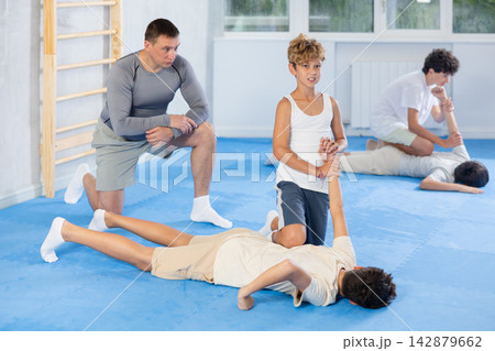 Diligent preteen student twisting his opponent's arm on the floor Diligent preteen student twisting his opponent's arm on the floor 142879662