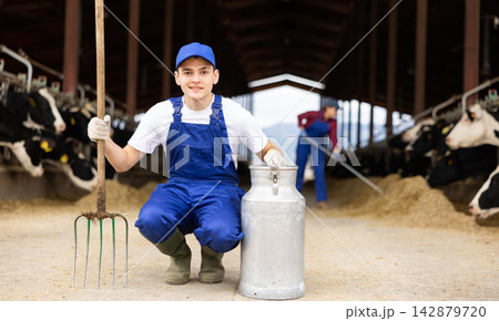 Young boy farmer with can works on dairy farm Young boy farmer with can works on dairy farm 142879720