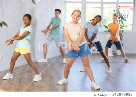 Smiling tween girl learning modern dynamic dances in choreography class Smiling tween girl learning modern dynamic dances in choreography class 142879956