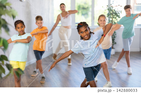 African boy dances vogue in choreographic school, friends and teacher dance in gym blurry background 142880033