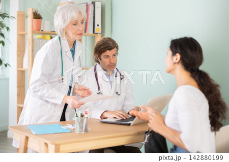 Happy woman discussing medical tests with female and male doctors 142880199