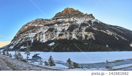 Panoramic Snowy Mountain and Frozen River with Evergreens in Winter Landscape Panoramic Snowy Mountain and Frozen River with Evergreens in Winter Landscape 142881082