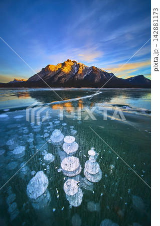 Frozen Methane Bubbles and Snowcapped Mountains Reflected on Winter Lake Surface Frozen Methane Bubbles and Snowcapped Mountains Reflected on Winter Lake Surface 142881173
