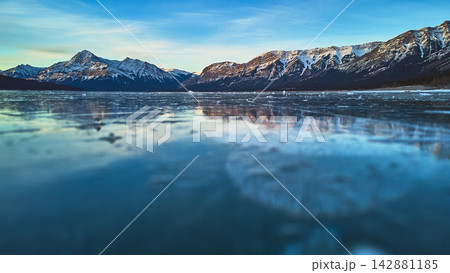 Frozen Lake Surface and Snow Capped Mountains at Sunrise in Winter Frozen Lake Surface and Snow Capped Mountains at Sunrise in Winter 142881185