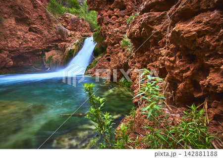 Hidden Waterfall Flowing Into Turquoise Pool With Red Canyon Walls And Green Plants Hidden Waterfall Flowing Into Turquoise Pool With Red Canyon Walls And Green Plants 142881188