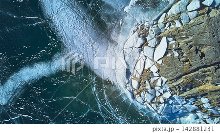 Aerial Frozen Lake Ice Pattern and Rocky Shoreline in Winter Top Down Aerial Frozen Lake Ice Pattern and Rocky Shoreline in Winter Top Down 142881231