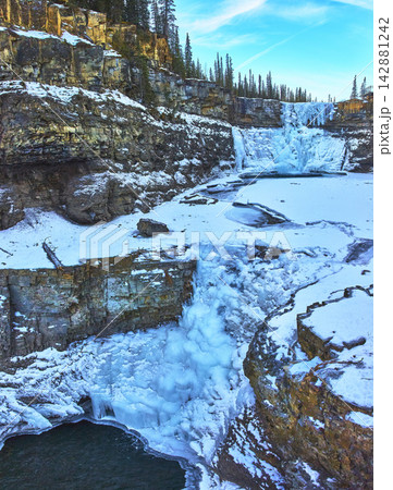 Frozen Crescent Falls Winter Panorama with Rocky Cliffs and Pine Forest Frozen Crescent Falls Winter Panorama with Rocky Cliffs and Pine Forest 142881242