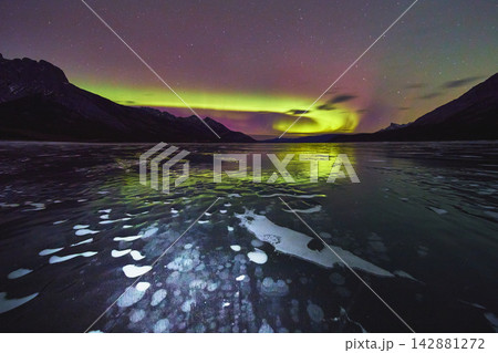 Northern Lights Over Frozen Lake With Ice Bubbles and Mountain Silhouette at Night Northern Lights Over Frozen Lake With Ice Bubbles and Mountain Silhouette at Night 142881272