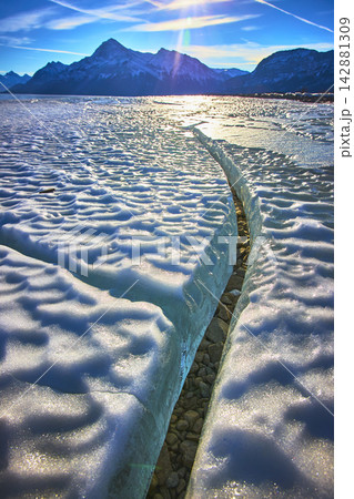 Frozen Lake Ice Crack Winter Mountain Landscape in Brilliant Sunlight Frozen Lake Ice Crack Winter Mountain Landscape in Brilliant Sunlight 142881309