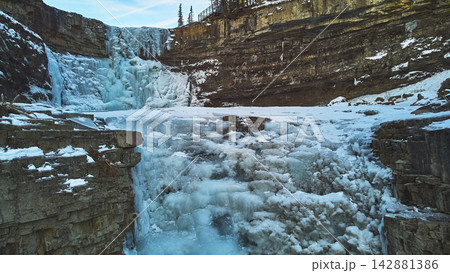 Frozen Waterfall and Rocky Canyon with Snowy Cliffs in Winter Aerial 142881386