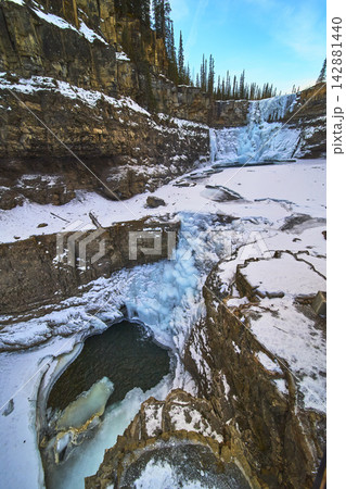 Frozen Waterfall and Rugged Canyon Walls in Winter Landscape with Snow and Ice Frozen Waterfall and Rugged Canyon Walls in Winter Landscape with Snow and Ice 142881440
