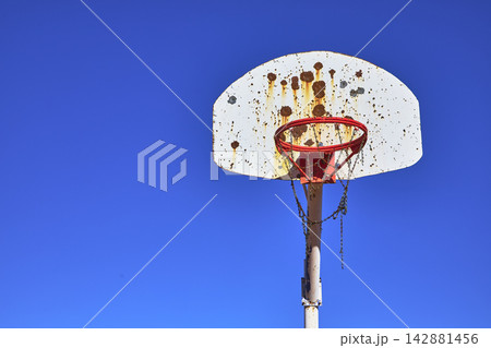 Old Outdoor Basketball Hoop Against Blue Sky with Rust and Chain Net Old Outdoor Basketball Hoop Against Blue Sky with Rust and Chain Net 142881456