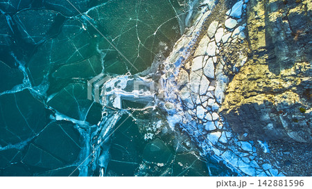 Aerial Frozen Lake Cracked Ice Patterns and Rocky Shoreline Winter Top Down Aerial Frozen Lake Cracked Ice Patterns and Rocky Shoreline Winter Top Down 142881596