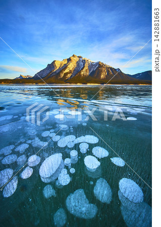 Frozen Lake Methane Bubbles and Snowy Mountains Under Blue Winter Sky Frozen Lake Methane Bubbles and Snowy Mountains Under Blue Winter Sky 142881663