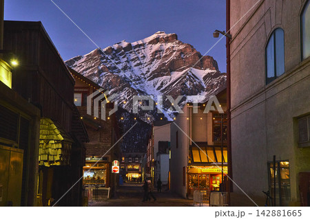 Banff Winter Town Street with Snowy Mountain and Evening Lights in Alberta Canada Banff Winter Town Street with Snowy Mountain and Evening Lights in Alberta Canada 142881665