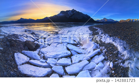 Panorama Frozen Lake with Cracked Ice and Snow Mountains at Winter Sunset 142881725