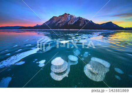 Frozen Methane Bubbles and Mountain Reflections on Winter Lake at Sunset 142881869