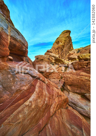 Colorful Sandstone Formations and Dramatic Pinnacle Under Vibrant Blue Sky Colorful Sandstone Formations and Dramatic Pinnacle Under Vibrant Blue Sky 142882060