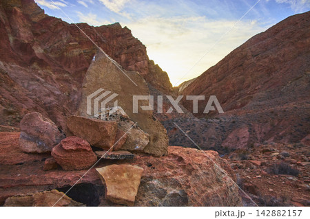 Rock Cairn in Desert Canyon at Sunrise with Dramatic Red Cliffs and Wide Open Sky 142882157