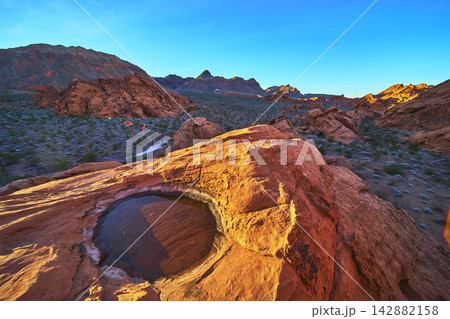 Sunrise Redstone Dune with Desert Tinaja Water Basin and Rugged Nevada Landscape 142882158