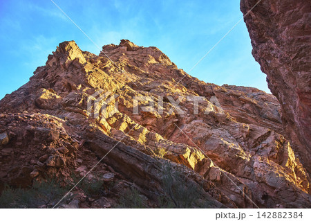 Sunlit Red Rock Formations in Dramatic Slot Canyon Against Blue Sky Sunlit Red Rock Formations in Dramatic Slot Canyon Against Blue Sky 142882384