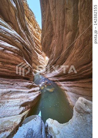 Slot Canyon Water Pool and Layered Sandstone Walls in Sunlit Desert Slot Canyon Water Pool and Layered Sandstone Walls in Sunlit Desert 142882555