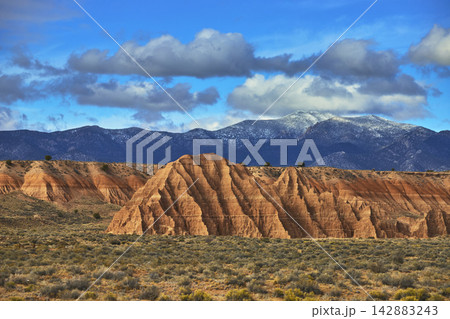Cathedral Gorge State Park Rock Formations with Snowcapped Mountains and Blue Sky Cathedral Gorge State Park Rock Formations with Snowcapped Mountains and Blue Sky 142883243