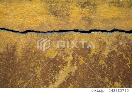 Full frame shot of cracked and dirty yellow wall. Wider cracks often represent serious structural damage and can cause serious issues. Full frame shot of cracked and dirty yellow wall. Wider cracks often represent serious structural damage and can cause serious issues. 142883759