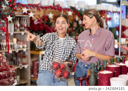 Two cheerful young women choosing Christmas decorations in store 142884181