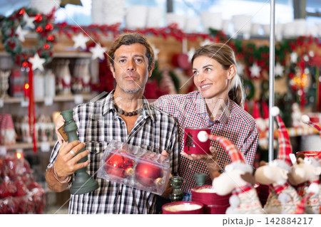 Couple having fun choosing festive Christmas decorations in store Couple having fun choosing festive Christmas decorations in store 142884217