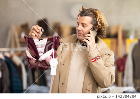Man search and choose bra and hanging on phone in store Man search and choose bra and hanging on phone in store 142884284