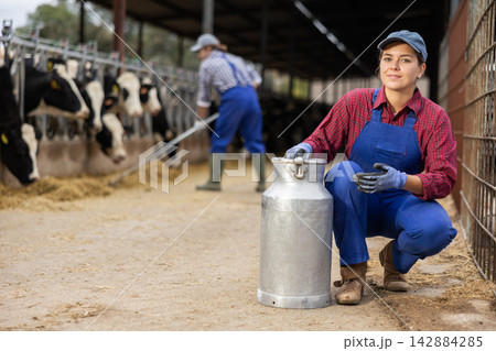 Young woman farmer with can works on dairy farm 142884285