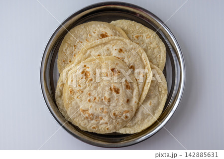 Homemade wheat flour phulka roti served on traditional metal plate. Authentic Bengali staple food item cooked for lunch and daily diet. Top view. Homemade wheat flour phulka roti served on traditional metal plate. Authentic Bengali staple food item cooked for lunch and daily diet. Top view. 142885631