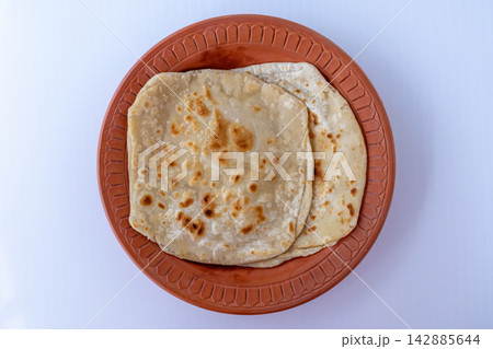 Delicious Plain Paratha Bread, Authentic Bangladeshi Breakfast Dish, Soft Layered Wheat Flatbread in Terracotta Plate, Traditional Homemade Food. Top view. 142885644