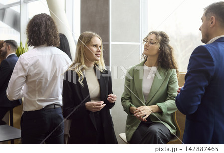 Diverse colleagues networking and discussing ideas at modern office lounge event Diverse colleagues networking and discussing ideas at modern office lounge event 142887465