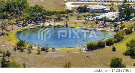 Scenic geothermal spring surrounded by nature, featuring saline water, swimmers floating peacefully, and a tranquil atmosphere connected to relaxation and healthy lifestyle. Scenic geothermal spring surrounded by nature, featuring saline water, swimmers floating peacefully, and a tranquil atmosphere connected to relaxation and healthy lifestyle. 142887466