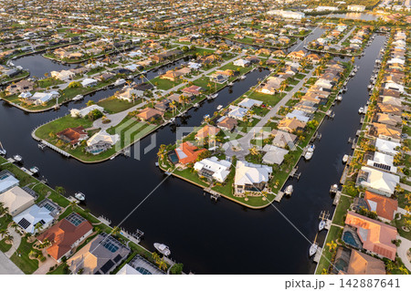 Sunset aerial view of Punta Gorda wealthy neighborhood. Expensive residential homes along canals reflect warm evening sky. 142887641