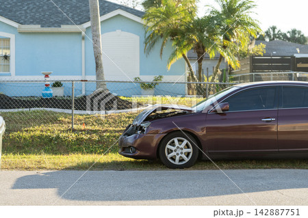 Crashed car with severe damage parked on residential street outside home after traffic accident. Transportation hazard concept. Crashed car with severe damage parked on residential street outside home after traffic accident. Transportation hazard concept. 142887751