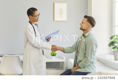Doctor and patient shaking hands after consultation in a bright modern clinic Doctor and patient shaking hands after consultation in a bright modern clinic 142887988