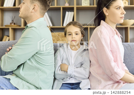Upset child between parents after argument, family conflict and tension at home Upset child between parents after argument, family conflict and tension at home 142888254