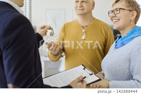 Happy senior couple getting keys from realtor after checking and signing agreement Happy senior couple getting keys from realtor after checking and signing agreement 142888444
