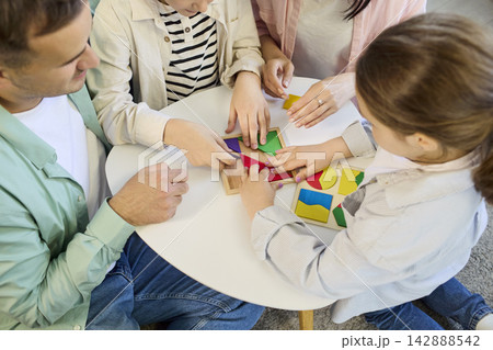 Parents and kids assembling geometric shapes puzzle game together at home Parents and kids assembling geometric shapes puzzle game together at home 142888542