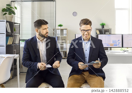 Two office employees compare salaries, one unhappy as colleague counts more cash Two office employees compare salaries, one unhappy as colleague counts more cash 142888552