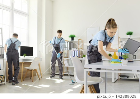 Professional cleaning team sanitizing office workspace with supplies and gloves 142889029